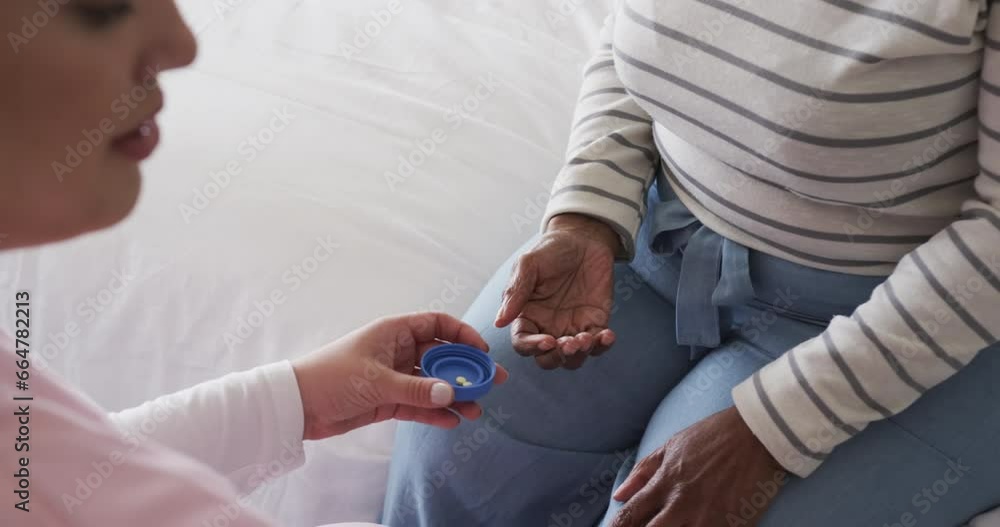 Caucasian female nurse giving pills to senior african american woman, copy space, slow motion Caucasian female nurse giving pills to senior african american woman, copy space, slow motion