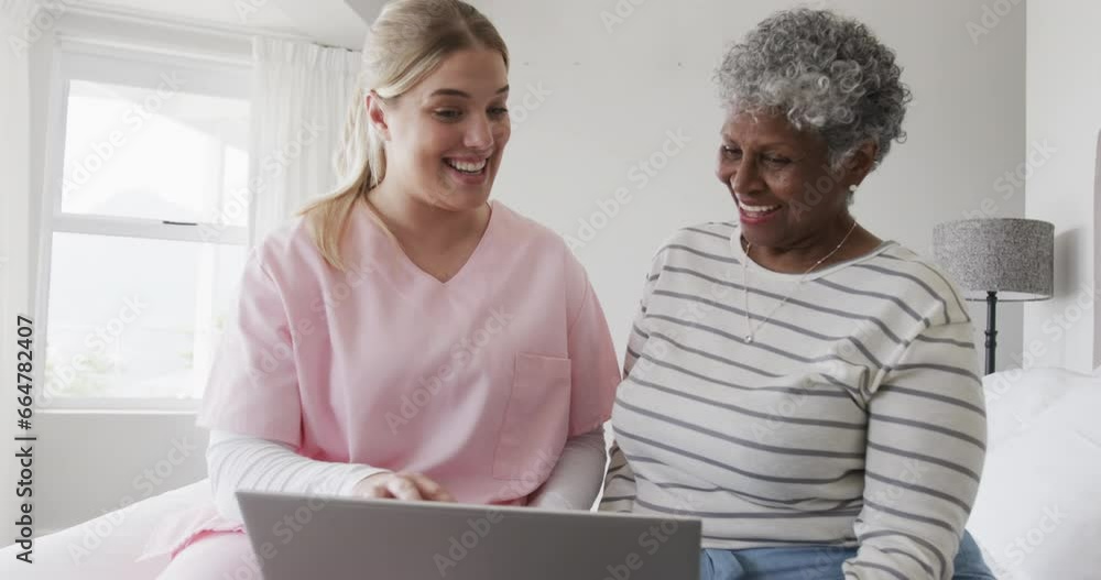 Caucasian female nurse and senior african american woman using laptop, copy space, slow motion Caucasian female nurse and senior african american woman using laptop, copy space, slow motion