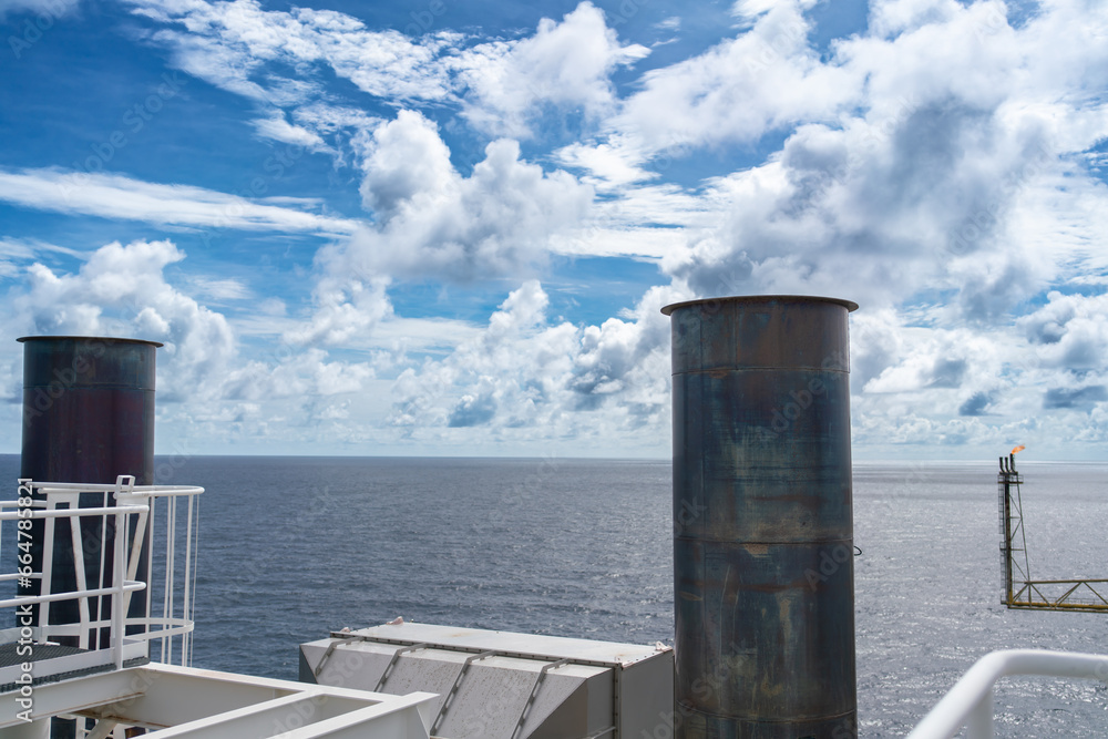 Obraz premium Smoke stacks from offshore gas and oil drilling rigs in the petroleum industry.