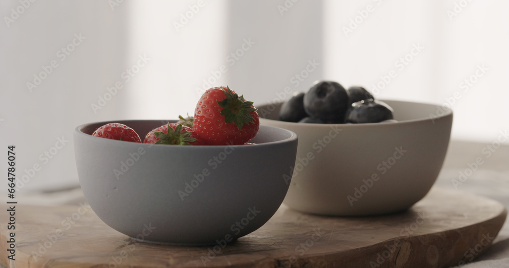 strawberries and blueberries in bowls on wood table strawberries and blueberries in bowls on wood table