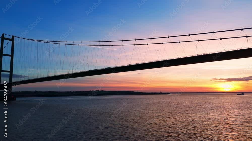 Humber Bridge bathed in the warmth of sunset, with cars seamlessly traversing its length, captured in a breathtaking aerial view. Humber Bridge bathed in the warmth of sunset, with cars seamlessly traversing its length, captured in a breathtaking aerial view.