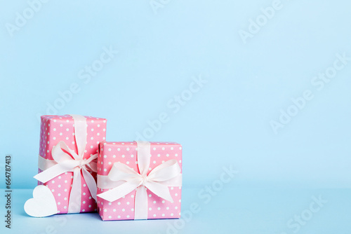 Fototapeta Naklejka Na Ścianę i Meble -  gift box with red bow and red heart on colored background. Perspective view. Flat lay