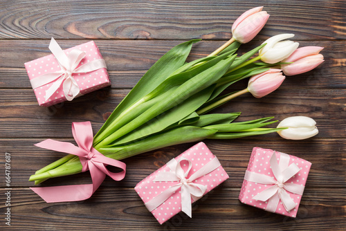 Pink tulips flowers and gift or present box on colored table background. Mothers Day, Birthday, Womens Day, celebration concept. Space for text top view