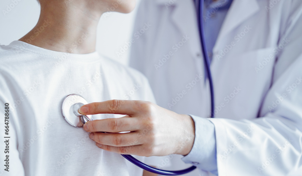 Unknown doctor and kid boy patient at usual medical inspection. Physician works using stethoscope, close up. Medicine, healthcare concepts Unknown doctor and kid boy patient at usual medical inspection. Physician works using stethoscope, close up. Medicine, healthcare concepts