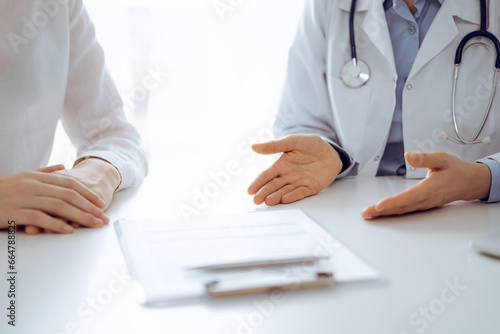 Doctor and patient discussing current health questions while sitting near of each other and using clipboard at the table in clinic  just hands closeup. Medicine concept