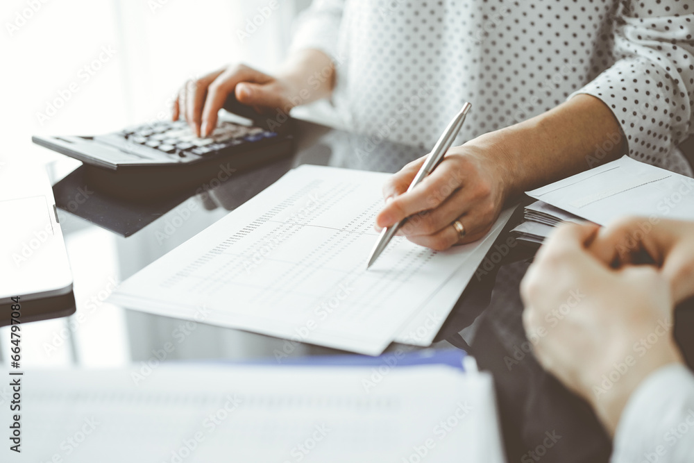 Woman accountant using a calculator and laptop computer while counting taxes for a client. Business audit and finance concepts Woman accountant using a calculator and laptop computer while counting taxes for a client. Business audit and finance concepts