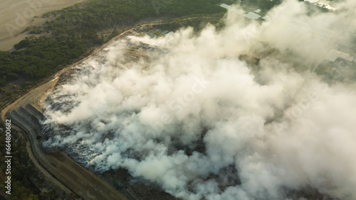 Top view of a fire at a landfill with plastic waste. An environmental disaster, toxic smoke from the fire pollutes the air. The importance of sorting and recycling waste. Let's save the planet. © moonmovie