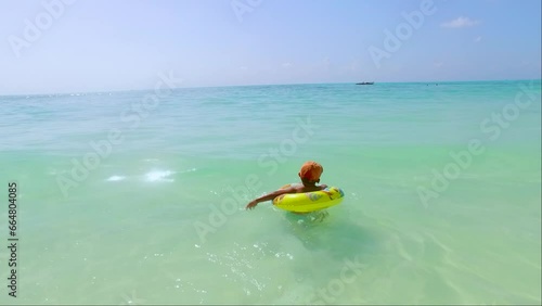 a child swims and plays with his buoy on the beach of jambiani zanzibar photo