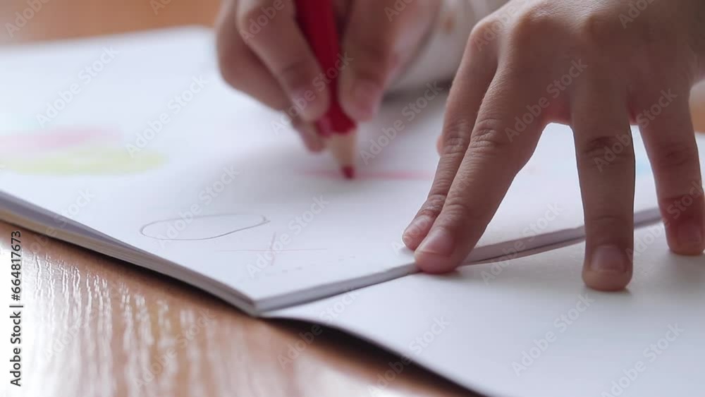 A child draws with colored pencils in an album. Children's creativity, learning in kindergarten, school or at home. Child's hand with a pencil close-up, selective focus. Girl draws a picture A child draws with colored pencils in an album. Children's creativity, learning in kindergarten, school or at home. Child's hand with a pencil close-up, selective focus. Girl draws a picture