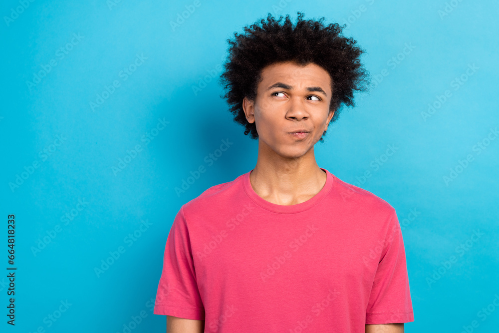 Photo of minded funky man wear pink stylish outfit looking offer empty space isolated on blue color background Photo of minded funky man wear pink stylish outfit looking offer empty space isolated on blue color background