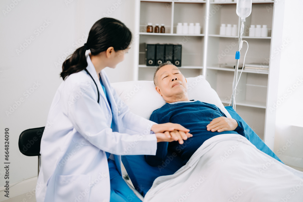 Asian doctor in white suit take notes while discussing and Asian elderly, man patient who lying on bed with receiving saline solution in hospital . Asian doctor in white suit take notes while discussing and Asian elderly, man patient who lying on bed with receiving saline solution in hospital .