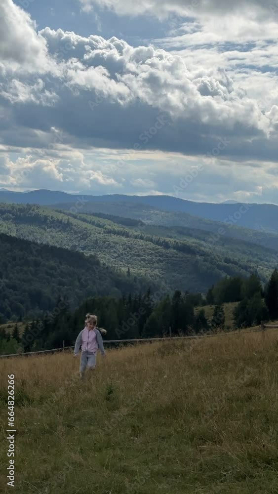 little cute girl running by meadow at the middle of mountains range little cute girl running by meadow at the middle of mountains range