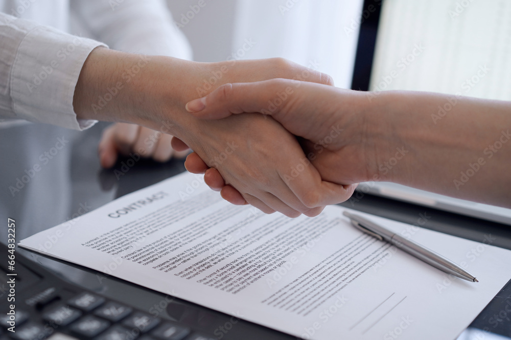 Business people shaking hands above contract papers just signed on the grey table, close up. Lawyers or entrepreneurs at meeting. Teamwork, partnership, success concept Business people shaking hands above contract papers just signed on the grey table, close up. Lawyers or entrepreneurs at meeting. Teamwork, partnership, success concept