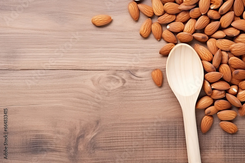 Almond nuts in wooden spoon on wooden background. Top view with copy space photo
