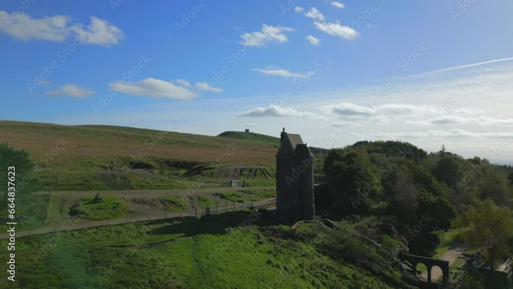 Lone stone tower building on hilltop, flight to and past towards hill with structure on top. Rivington, Lancashire, England, UK.
