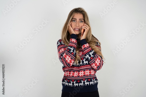 Afraid funny Young beautiful woman holding telephone and bitting nails photo