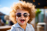 Little girl with big smile and sunglasses on her face.
