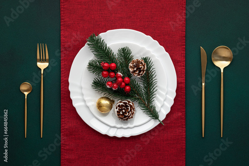 Festive table setting, christmas decoration. Dishware, golden cutlery. Celebration xmas eve: exquisite arrangement, red accent. Gold bauble, fir cones, evergreen tree. Holiday banquet, view from above