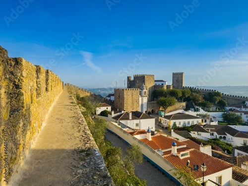 a wall along a road next to the beach near a castle