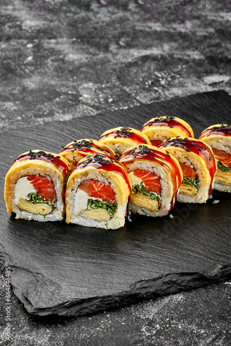 Sushi roll with salmon, omelet with unagi sauce on a concrete background