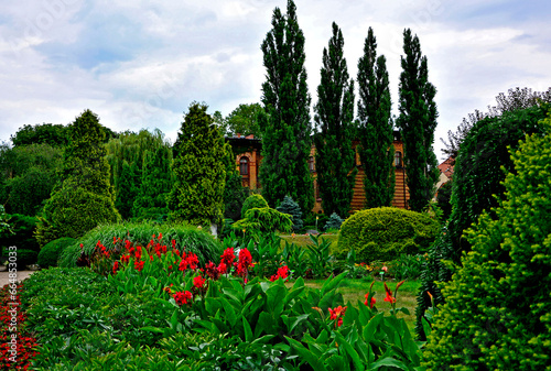 ogród, krzewy i kanny, ceglany budynek w ogrodzie , Canna or canna lily, czerwony paciorecznik, kanna, designer garden 