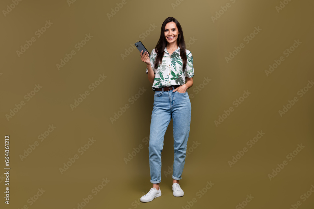 Full body photo of lovely cheerful lady hold smart phone chatting empty space isolated on brown color background Full body photo of lovely cheerful lady hold smart phone chatting empty space isolated on brown color background