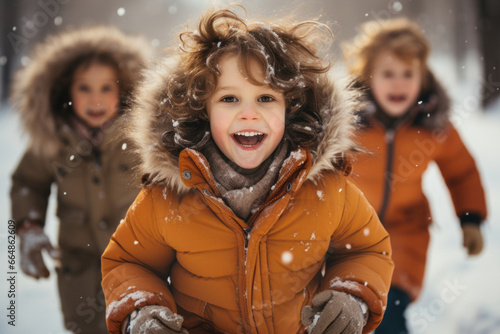 Happy little children playing in a snowfall on sunny winter day.