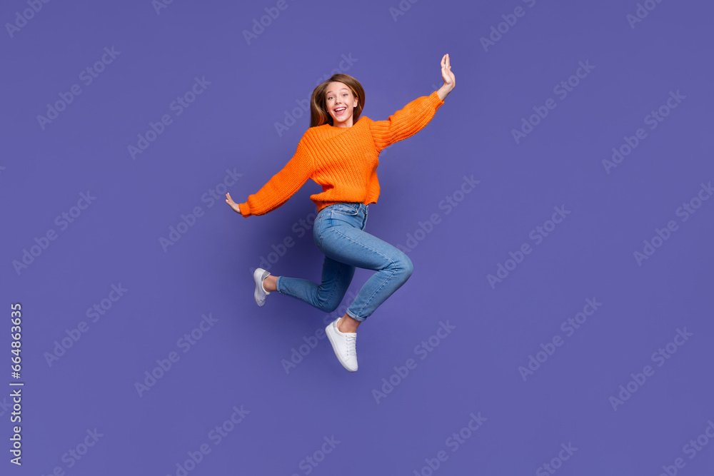 Full length photo of running jumper teen girl flying with hands like wings carefree spending weekend isolated on purple color background