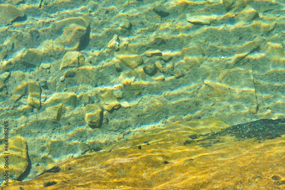pebbles on a turquoise green lake in the French Pyrenees