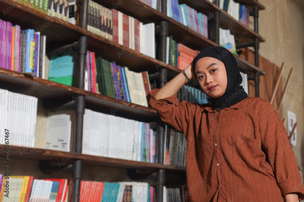 Portrait of Asian hijab woman holding book in front of library ...