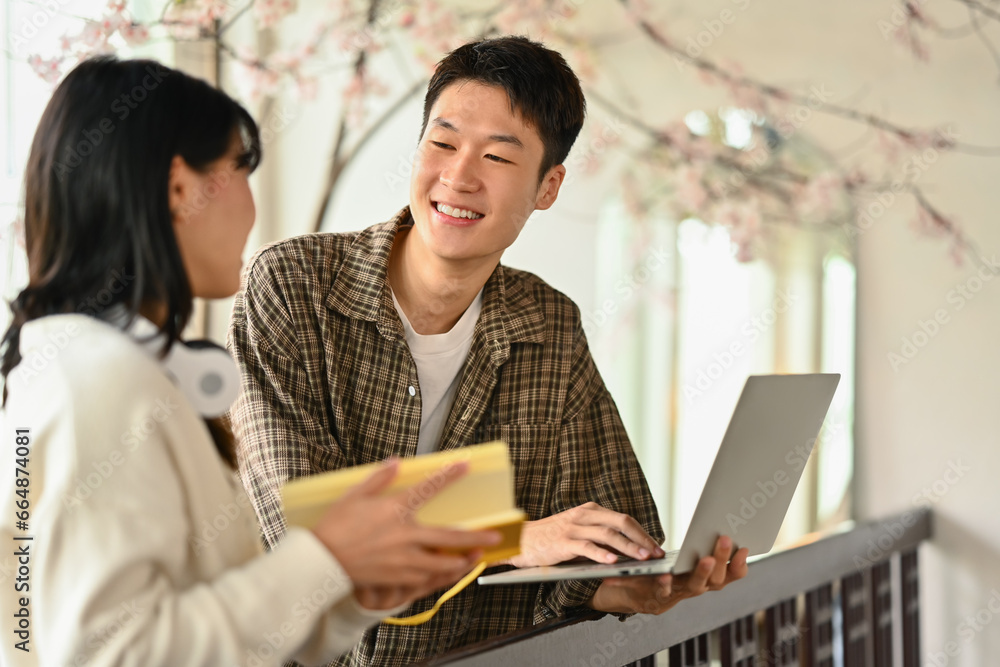 University students using laptop for researching online, collaborating on a project in campus University students using laptop for researching online, collaborating on a project in campus