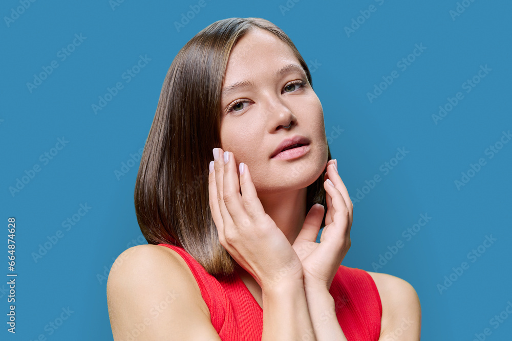 Young woman with natural makeup, with trendy nose piercing jewelry on blue background Young woman with natural makeup, with trendy nose piercing jewelry on blue background