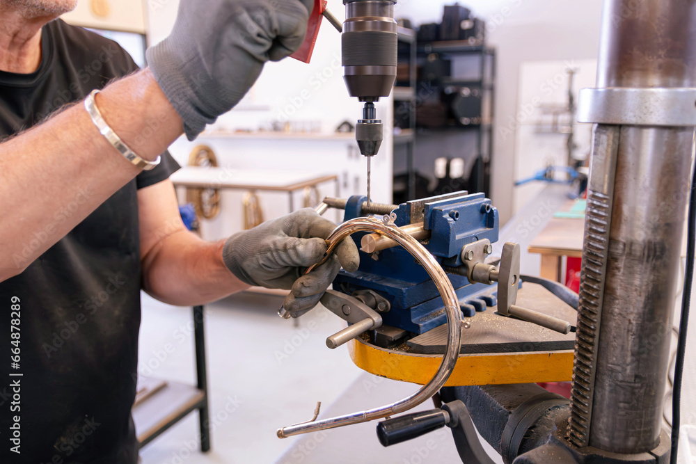 repairer of brass musical instruments using a vertical drill to restore