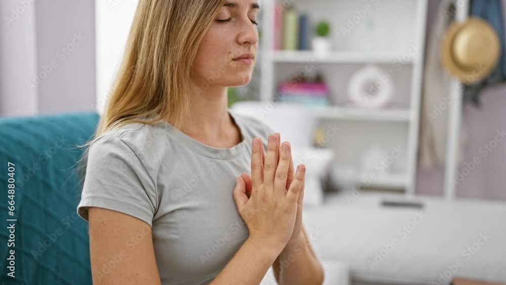 Attractive young blonde woman sitting in comfort on her living room sofa, deep in prayer and relaxation, home portraying a cozy atmosphere of faith and hope Attractive young blonde woman sitting in comfort on her living room sofa, deep in prayer and relaxation, home portraying a cozy atmosphere of faith and hope