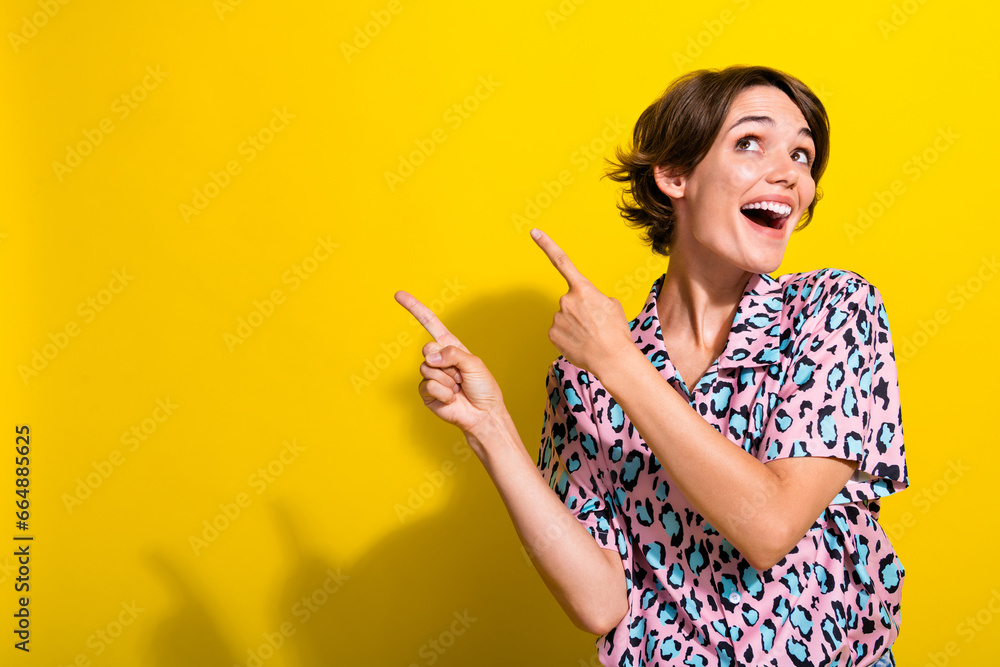 Photo of astonished cute person look indicate fingers empty space news isolated on yellow color background Photo of astonished cute person look indicate fingers empty space news isolated on yellow color background