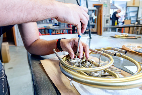 close-up repairing the machinery of a French horn in a brass musical instrument workshop