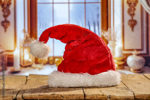 Red santa claus on wooden desk and winter window background in home interior. Cold december time and empty space for your products. 