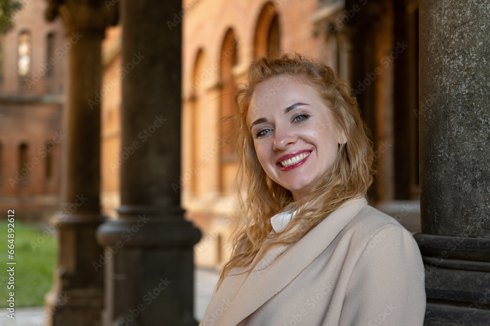 Portrait of happy young attractive woman with blue eyes and red curly hair is smiling. Natural beauty, walk in old city Portrait of happy young attractive woman with blue eyes and red curly hair is smiling. Natural beauty, walk in old city