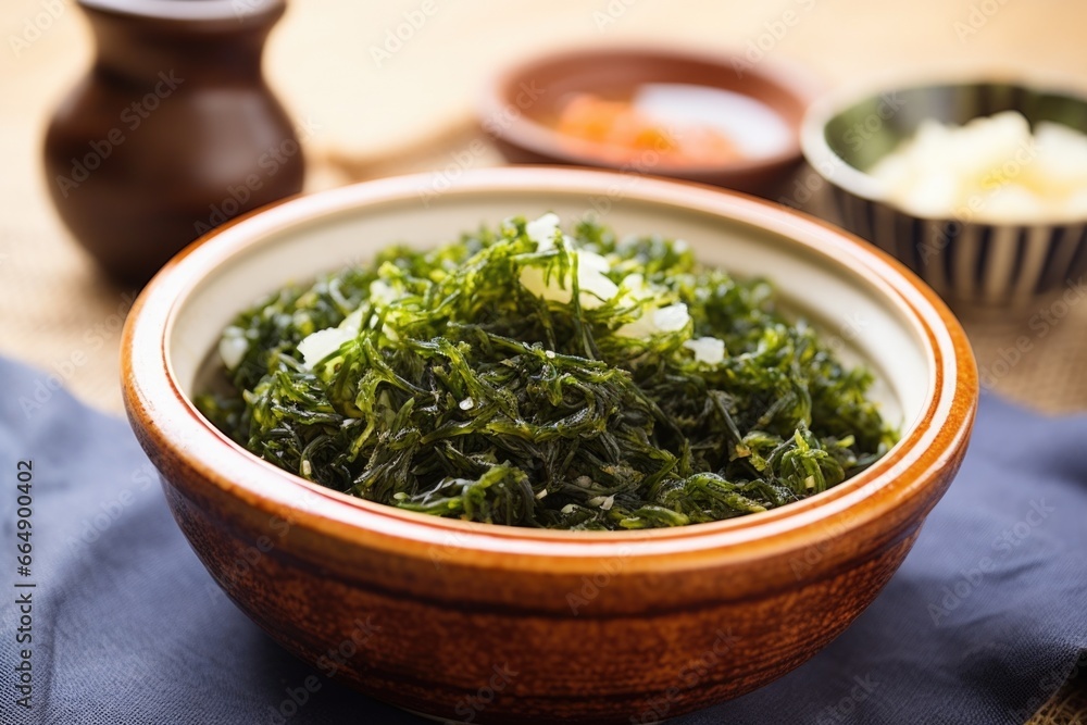 seaweed salad in a ceramic seashell bowl on a sandy textured tabletop seaweed salad in a ceramic seashell bowl on a sandy textured tabletop