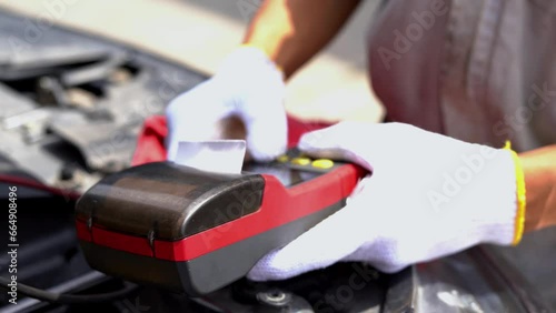 Mechanic Asian man checks the condition of the car battery