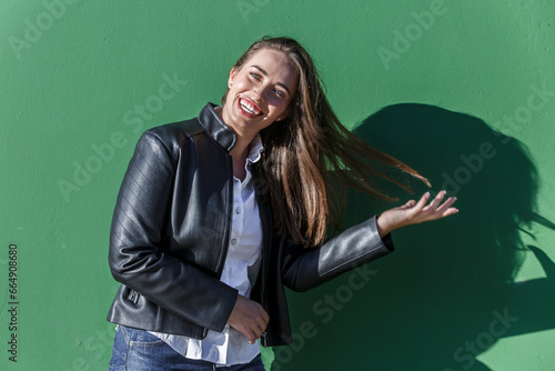 Cheerful woman flipping hair against green wall © Juan Algar
