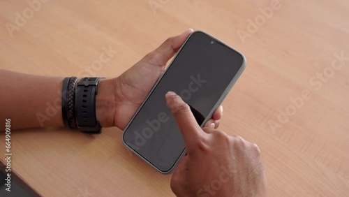 Mockup image of a hand holding mobile phone with blank screen on wooden table