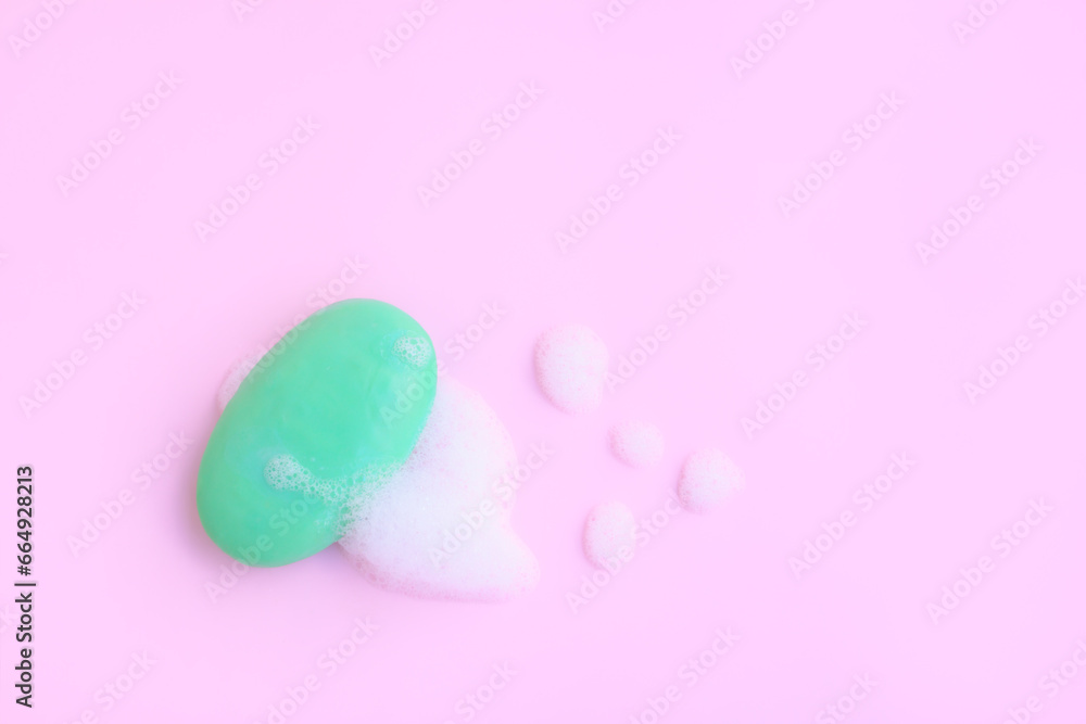 Green soap bar with soap foam on pink background, Soap and bubble, Top view