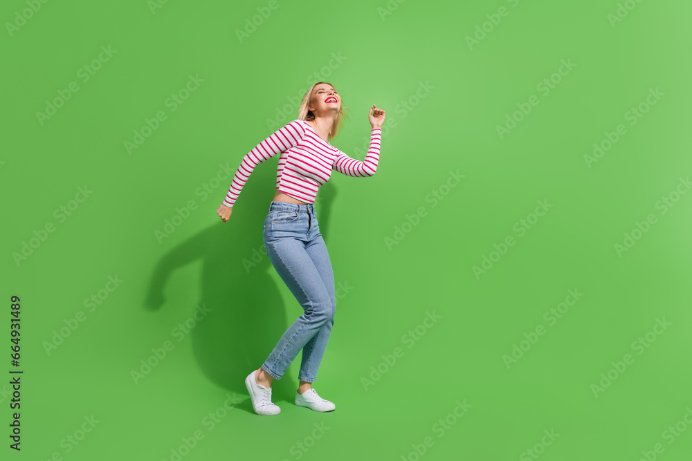 Full length photo of sweet positive girl dressed striped shirt dancing discotheque empty space isolated green color background Full length photo of sweet positive girl dressed striped shirt dancing discotheque empty space isolated green color background