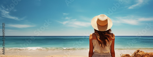 Back view of woman on the beach looking at the ocean, enjoying sun, tropical resort, freedom and leisure, beautiful sunny lifestyle, trendy travel. With copy space.  © Chrixxi