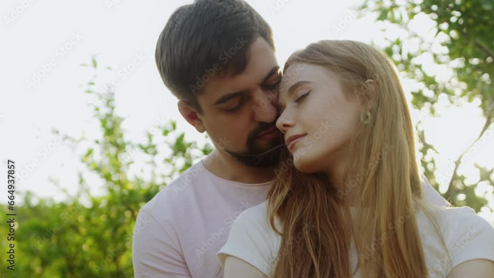 Mman hugging from back his girlfriend, woman putting head on boyfriend's shoulder at sunrise standing outdoors. Love, youth, happiness concept. Mman hugging from back his girlfriend, woman putting head on boyfriend's shoulder at sunrise standing outdoors. Love, youth, happiness concept.