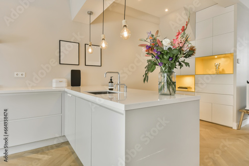 a modern kitchen with white cabinets and an island in the middle part of the room there is a vase of flowers