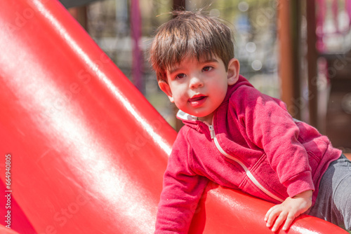 Child having fun climbing the slide in the playground. © fotosdanielgbueno