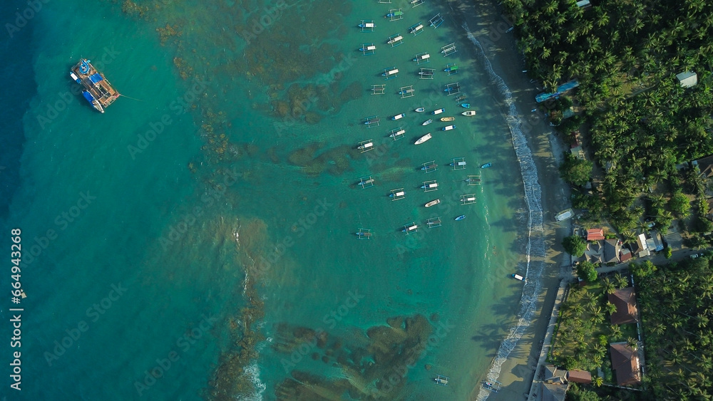 Aerial view of boats for diving trips parked off the shore of the tropical island of Bali. Colorful boats for diving trips near the beach, top-down view. Adventure and travel concept.