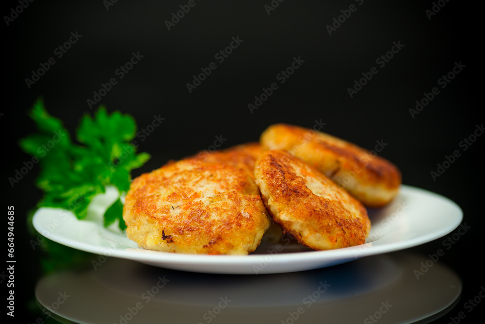 Cooked fried fish cutlets in a plate with herbs.